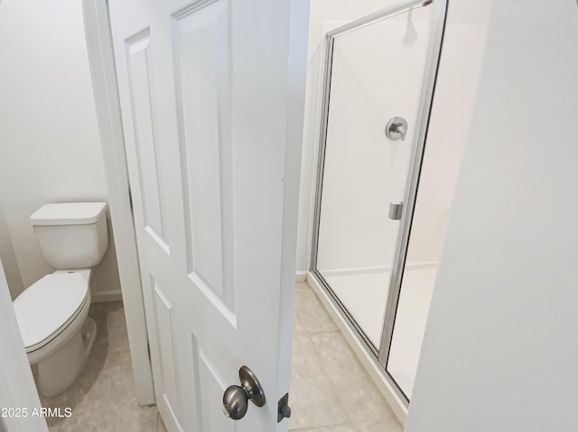 bathroom with tile patterned floors, toilet, and a shower stall