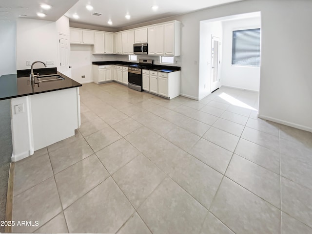 kitchen with a sink, dark countertops, recessed lighting, appliances with stainless steel finishes, and baseboards