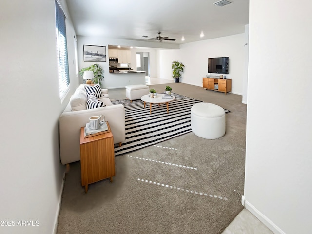 living room featuring visible vents, baseboards, and a ceiling fan