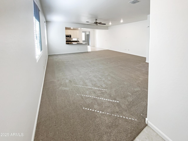 unfurnished living room featuring visible vents, baseboards, carpet, and a ceiling fan