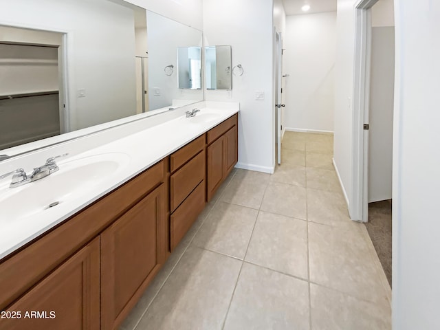 full bath with a sink, baseboards, double vanity, and tile patterned floors