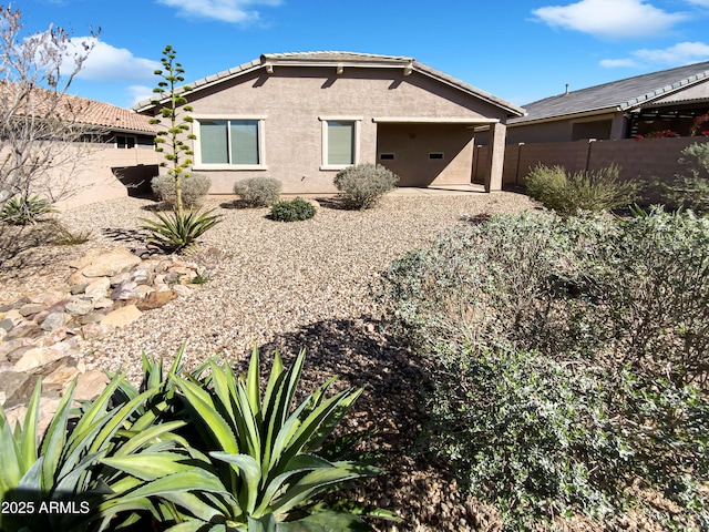 back of house featuring a tiled roof, stucco siding, and fence