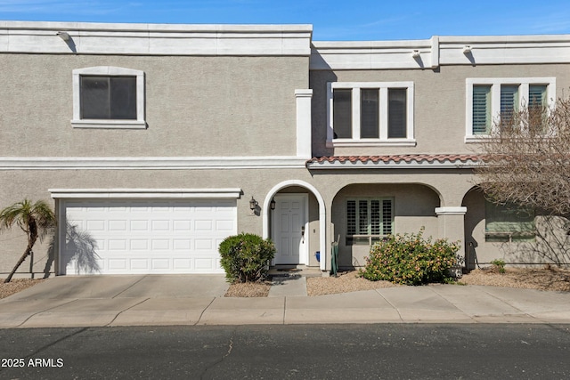 view of property featuring concrete driveway, a garage, and stucco siding