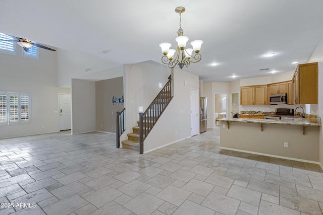 kitchen featuring light stone counters, baseboards, a peninsula, stainless steel appliances, and open floor plan