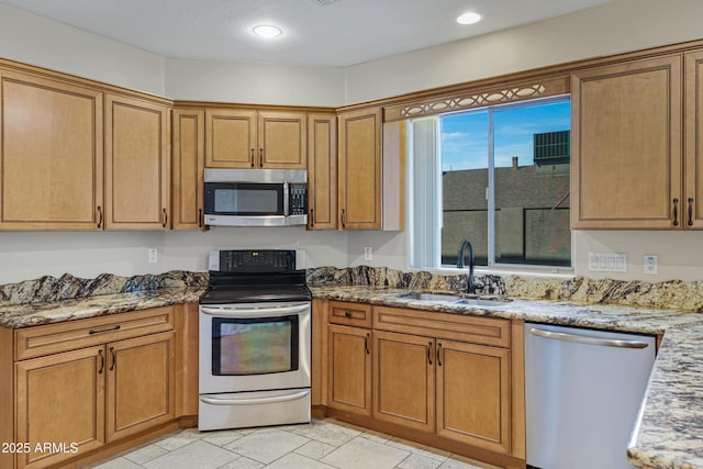 kitchen featuring light stone counters, brown cabinets, appliances with stainless steel finishes, and a sink