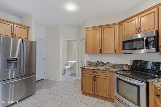 kitchen with stone counters, stainless steel appliances, baseboards, and brown cabinets