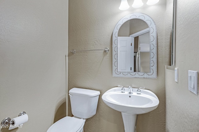 half bath featuring toilet and a textured wall