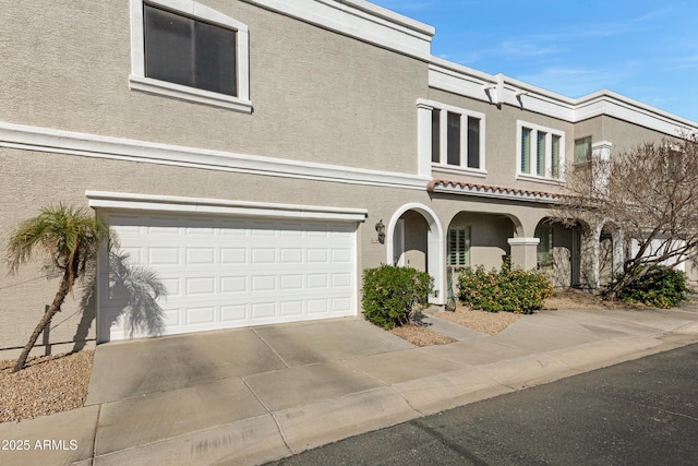 view of front facade featuring a garage, driveway, and stucco siding