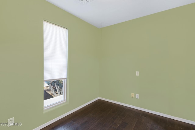 empty room featuring visible vents, dark wood-style floors, and baseboards