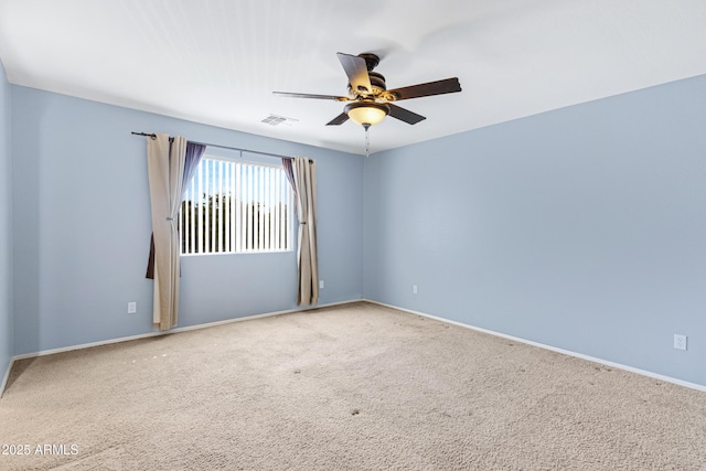 carpeted spare room with visible vents, baseboards, and a ceiling fan