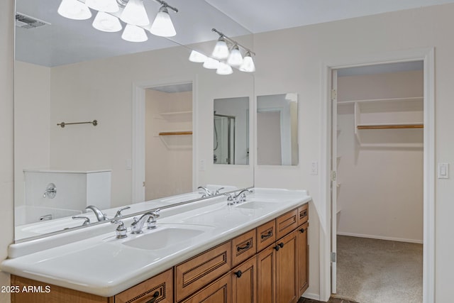 bathroom with a sink, visible vents, a walk in closet, and double vanity