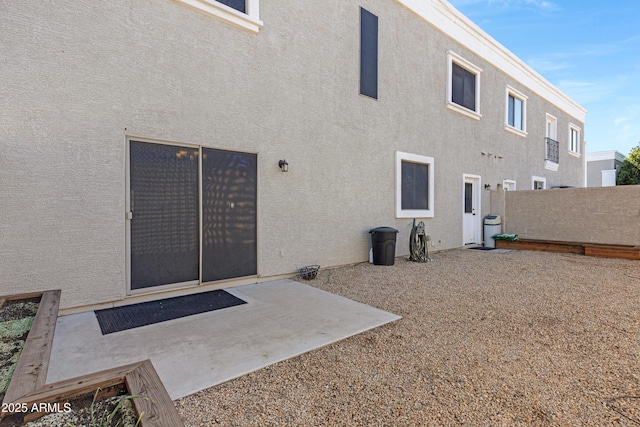 rear view of property featuring a patio, fence, and stucco siding