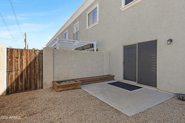 property entrance featuring a patio area, stucco siding, a gate, and fence