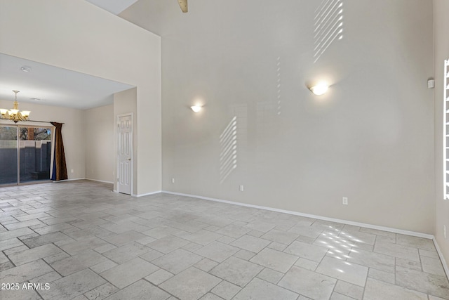 empty room with a chandelier, stone finish floor, and baseboards