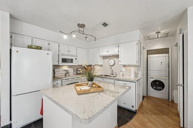 kitchen featuring white cabinetry, stacked washing maching and dryer, white appliances, and a kitchen island