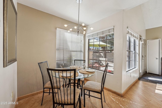 dining space with hardwood / wood-style floors and a notable chandelier