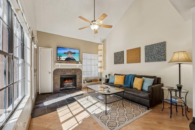 living room with high vaulted ceiling, a wealth of natural light, hardwood / wood-style flooring, and a fireplace