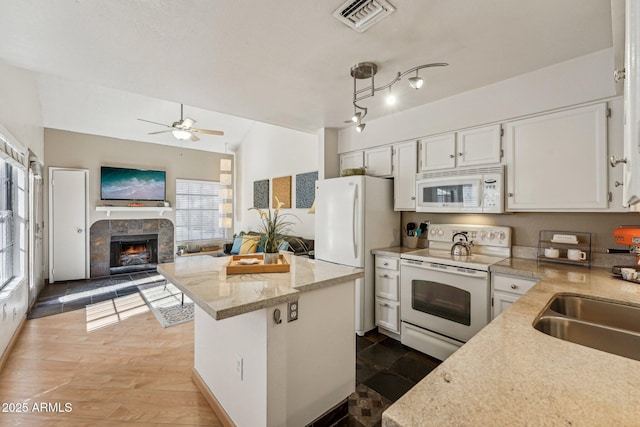 kitchen featuring white appliances, white cabinetry, a kitchen island, decorative light fixtures, and a fireplace