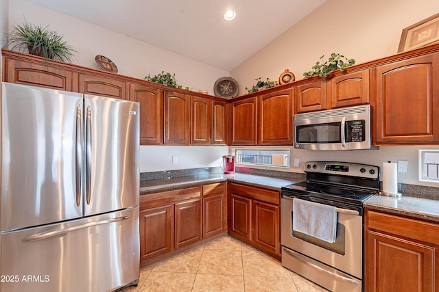 kitchen with light tile patterned floors, appliances with stainless steel finishes, dark stone counters, and vaulted ceiling