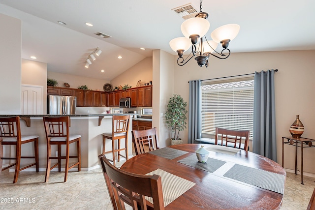 dining room with rail lighting, vaulted ceiling, and a notable chandelier