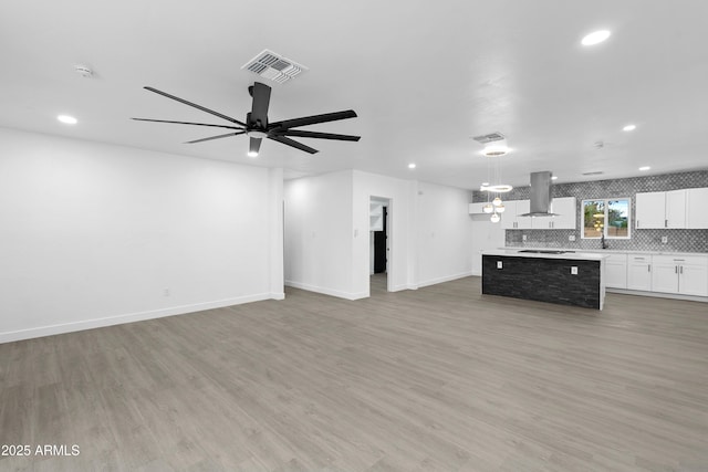 unfurnished living room with a ceiling fan, light wood-style floors, visible vents, and baseboards