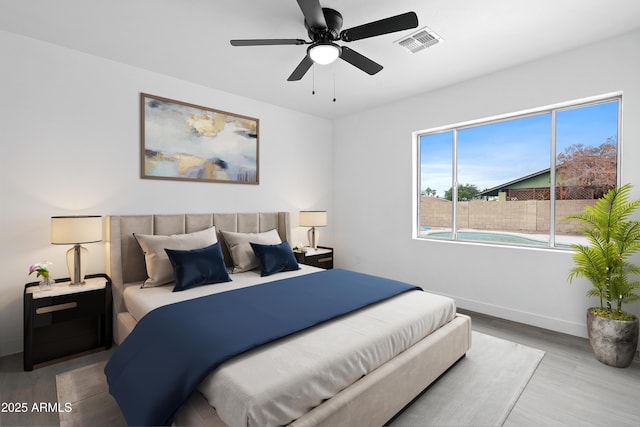 bedroom with ceiling fan, wood finished floors, visible vents, and baseboards