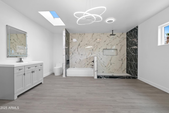 bathroom featuring a marble finish shower, a skylight, vanity, and wood finished floors