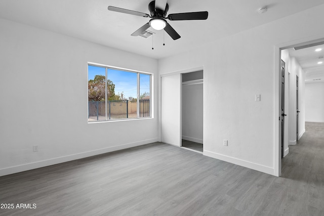 unfurnished bedroom featuring a closet, ceiling fan, baseboards, and wood finished floors