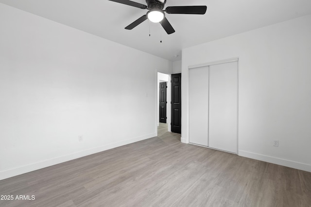 unfurnished bedroom featuring a closet, baseboards, light wood finished floors, and ceiling fan