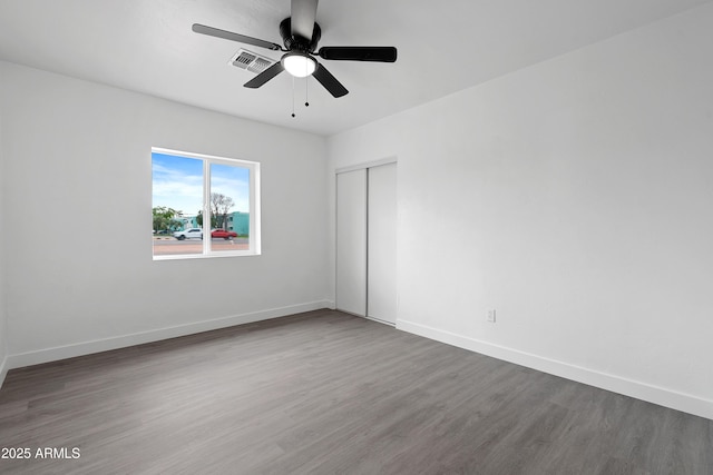 spare room featuring a ceiling fan, wood finished floors, visible vents, and baseboards