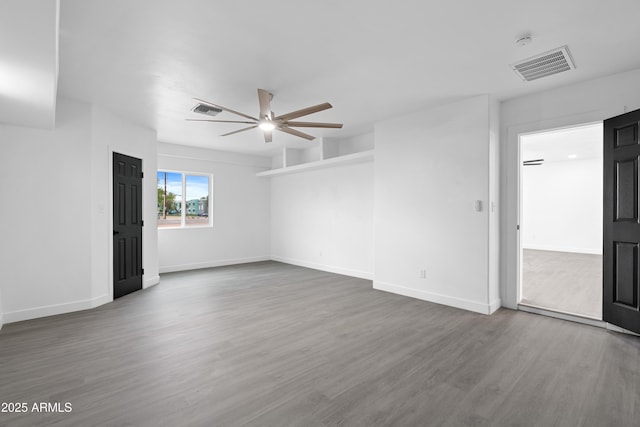 spare room with ceiling fan, visible vents, baseboards, and wood finished floors