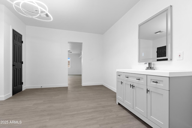 interior space with visible vents, a notable chandelier, light wood-style flooring, a sink, and baseboards