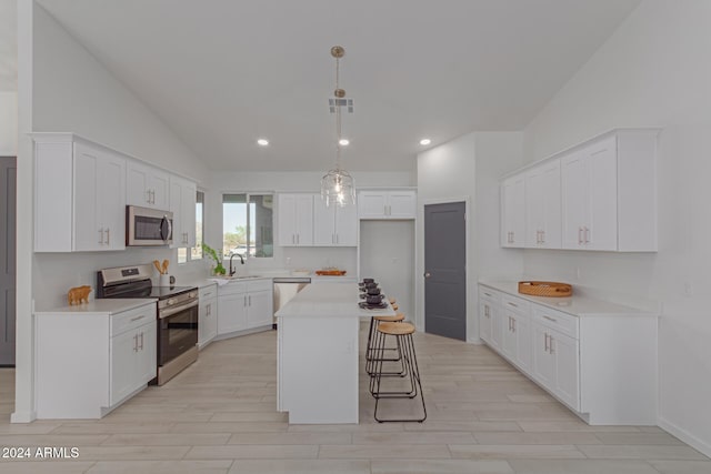 kitchen featuring a center island, white cabinets, stainless steel appliances, and lofted ceiling