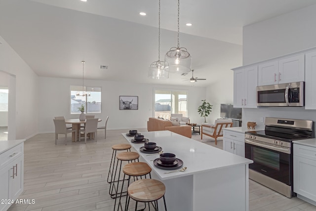 kitchen featuring pendant lighting, stainless steel appliances, white cabinetry, and a wealth of natural light