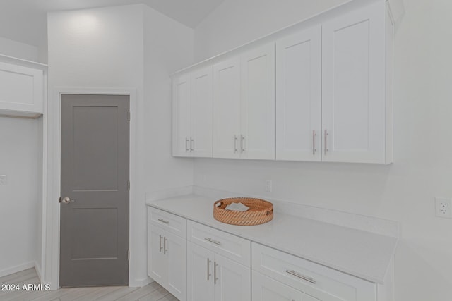 kitchen featuring white cabinets, light wood-type flooring, and light stone countertops