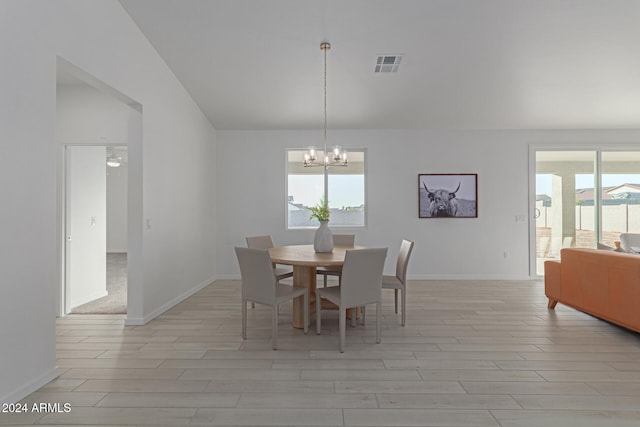 dining room featuring plenty of natural light, ceiling fan with notable chandelier, light hardwood / wood-style floors, and vaulted ceiling