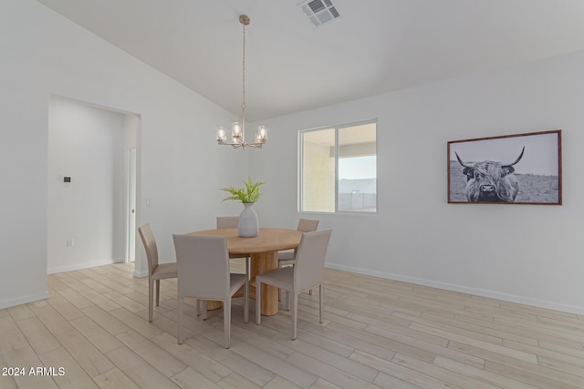 dining room with a chandelier, light hardwood / wood-style flooring, and vaulted ceiling