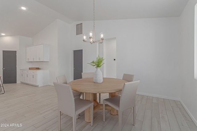 dining area featuring a notable chandelier, high vaulted ceiling, and light hardwood / wood-style flooring