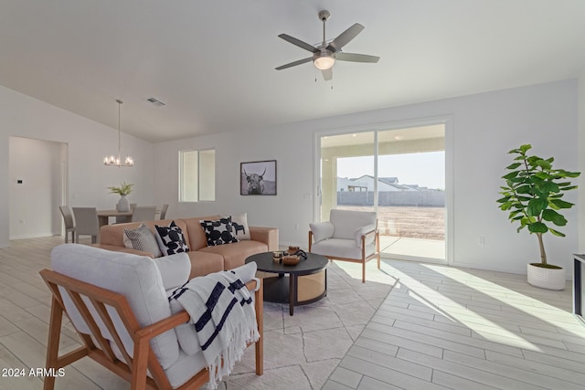 living room with ceiling fan with notable chandelier, light hardwood / wood-style floors, and lofted ceiling