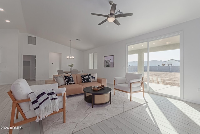 living room with a mountain view, ceiling fan with notable chandelier, vaulted ceiling, and light wood-type flooring