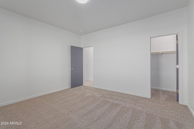 unfurnished bedroom featuring light colored carpet, a spacious closet, and a closet