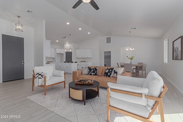 living room with ceiling fan with notable chandelier, light hardwood / wood-style floors, and vaulted ceiling