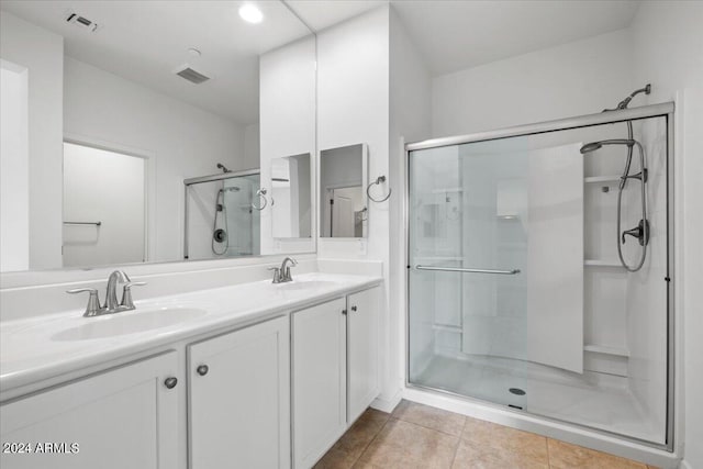 bathroom with tile patterned floors, a shower with door, and double sink vanity