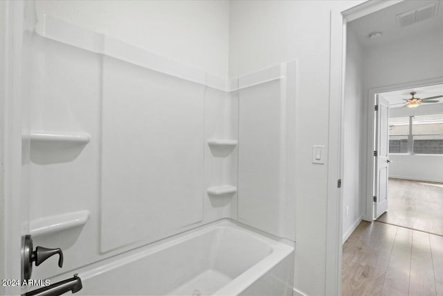 bathroom with hardwood / wood-style flooring, bathing tub / shower combination, and ceiling fan