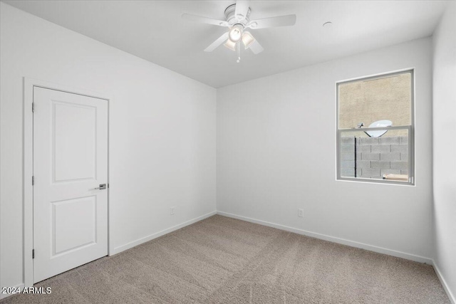 carpeted spare room featuring ceiling fan