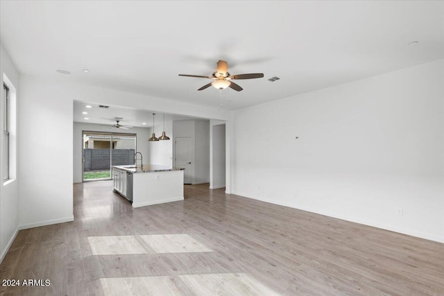 unfurnished living room with light hardwood / wood-style flooring, sink, and ceiling fan