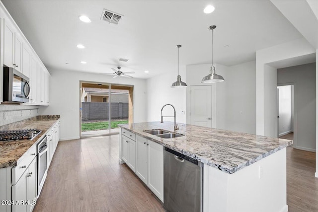 kitchen featuring stainless steel appliances, white cabinets, sink, light hardwood / wood-style flooring, and a kitchen island with sink