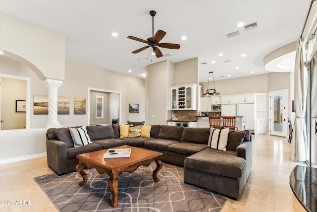 living room with ceiling fan, decorative columns, a high ceiling, and light tile patterned floors