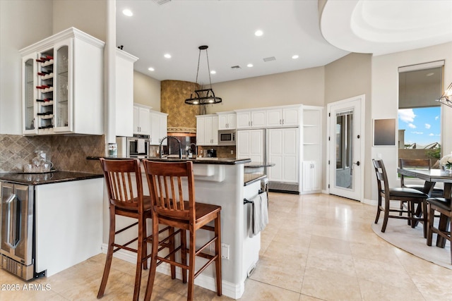 kitchen with a breakfast bar, pendant lighting, tasteful backsplash, white cabinetry, and stainless steel appliances