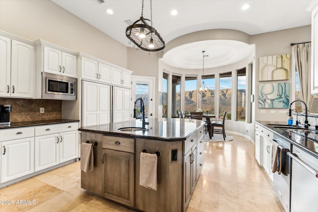 kitchen with white cabinetry, appliances with stainless steel finishes, sink, and a center island with sink